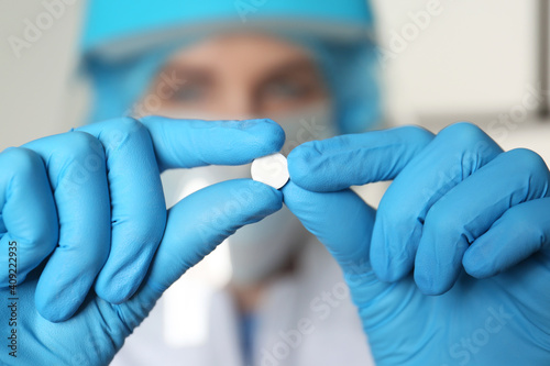 Scientist in protective gloves holding pill, closeup view