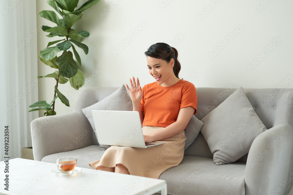 Young woman showing hello gesture to somebody talking by internet Young woman showing hello gesture to somebody talking by internet