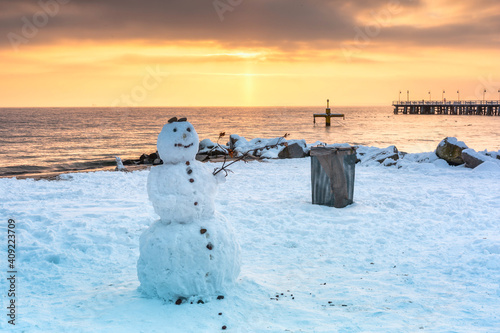 Fototapeta Naklejka Na Ścianę i Meble -  Snowman on the beach of the Baltic Sea in winter at sunrise, Gdynia Orłowo. Poland.