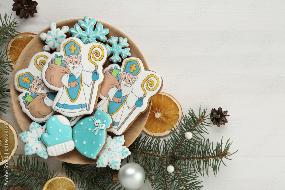 Tasty gingerbread cookies and festive decor on white table, flat lay. St. Nicholas Day celebration