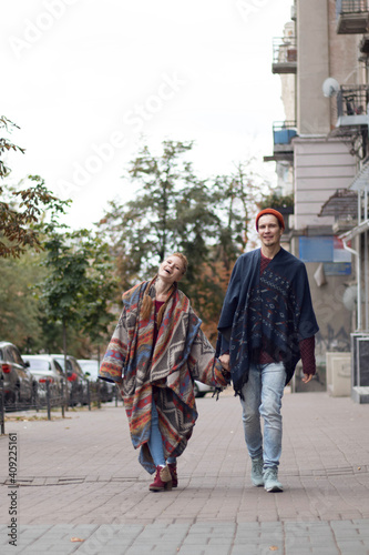 Vertical photo, red-haired guy and girl in unusual clothes, couple in love on the street