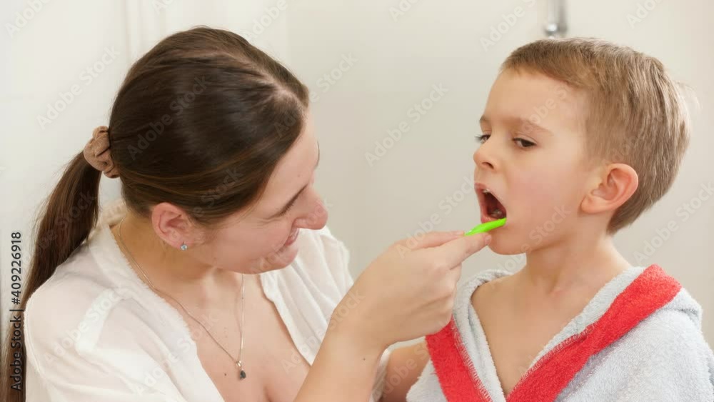 Young smiling mother brushing and cleaning teeth of her little son with tothbrush. Concept of child dental hygiene and healthcare at home. Caring parents and kids at home. Young smiling mother brushing and cleaning teeth of her little son with tothbrush. Concept of child dental hygiene and healthcare at home. Caring parents and kids at home.