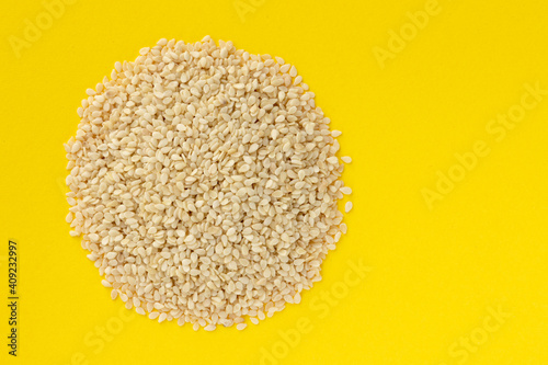 White sesame seeds heap isolated on yellow background. photo