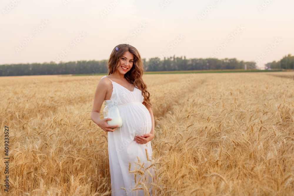 a pregnant woman with a can of milk walks in a wheat field a pregnant woman with a can of milk walks in a wheat field