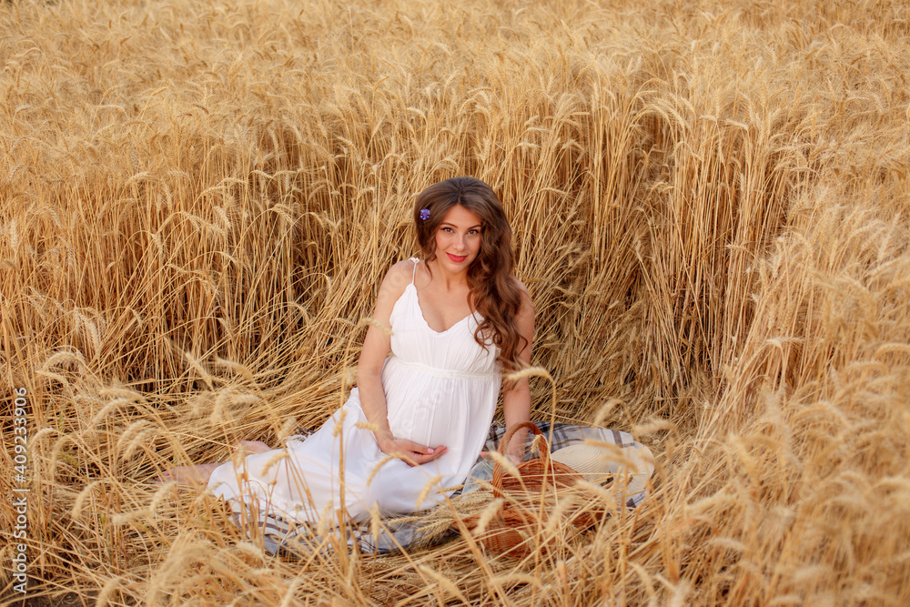 pregnant woman sitting in a field of wheat a picnic pregnant woman sitting in a field of wheat a picnic