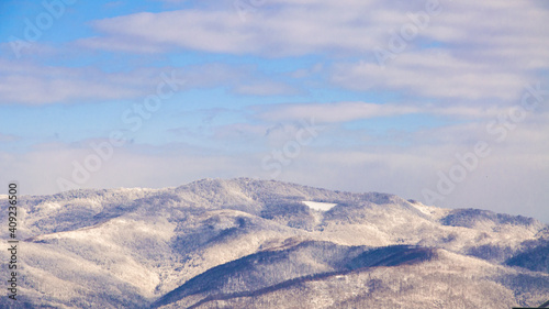 Hills covered with snow and cloudy sky, winter composition, snow falling, frozen nature, winter time background