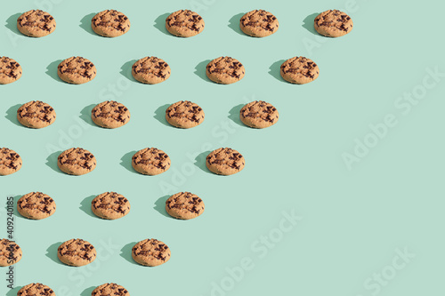 Trendy pattern made of chocolate chip cookies on bright green mint background. Minimal concept, diagonal copy space.