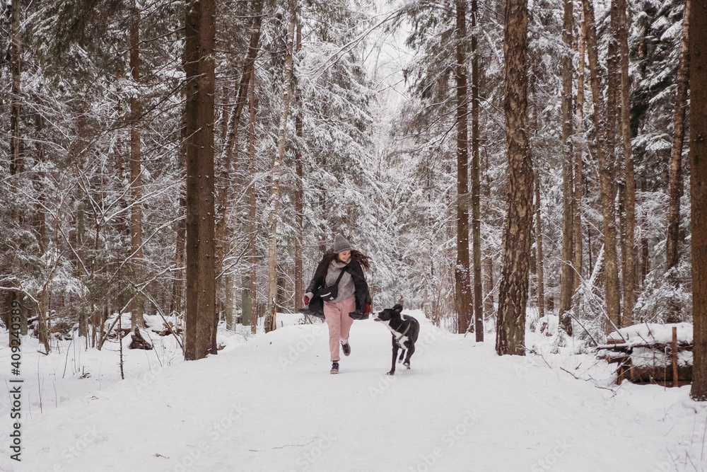 Young woman playing with her dog at winter forest. Lifestyle with dog