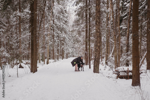 Young woman playing with her dog at winter forest. Lifestyle with dog