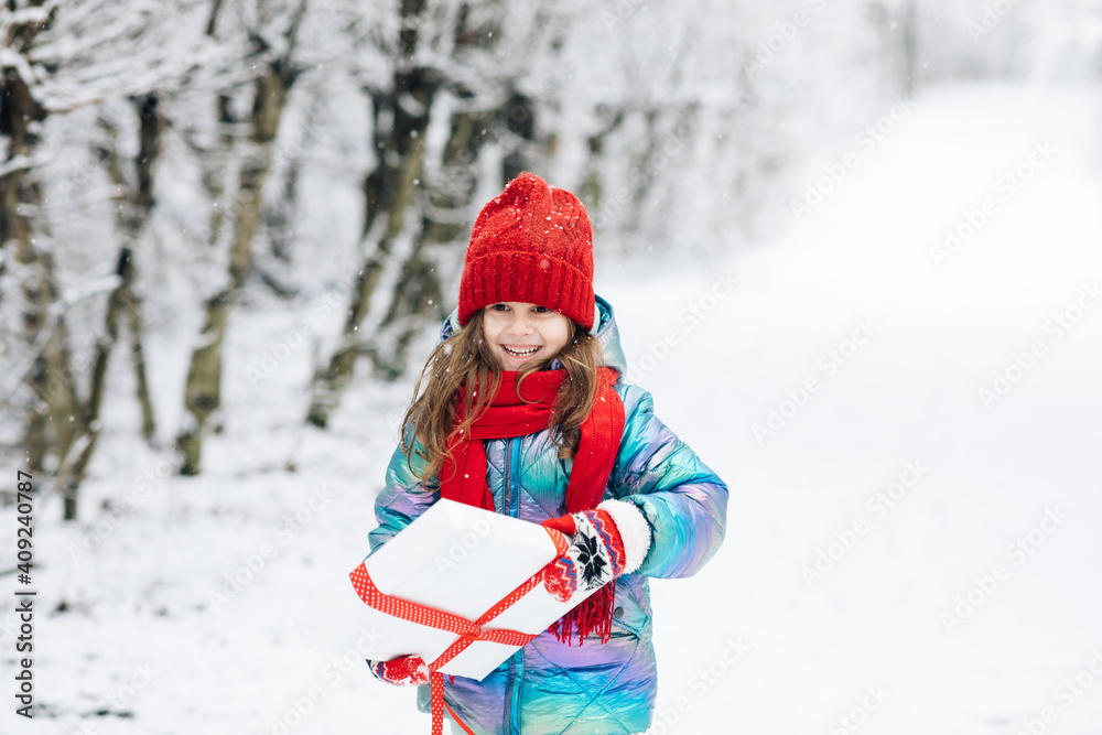 Little girl with christmas box gift in winter outdoors on Xmas eve. Happy Little caucasian girl smile and holding gift box in Christmas day. Child holding gift box and surprise face