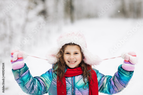 Happy child girl plays with a snow in winter day. Girl enjoys winter, frosty day. Playing with snow on winter holidays. Walk in winter forest