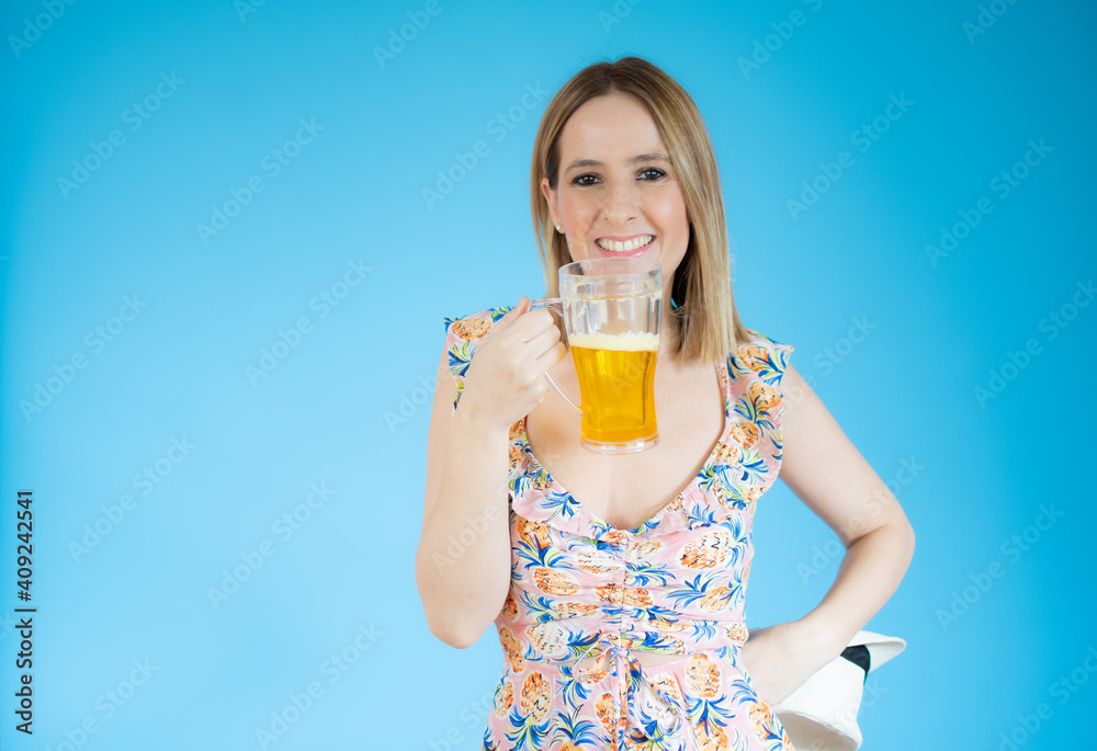 Beautiful young woman holding glass of beer over blue background. Beautiful young woman holding glass of beer over blue background.