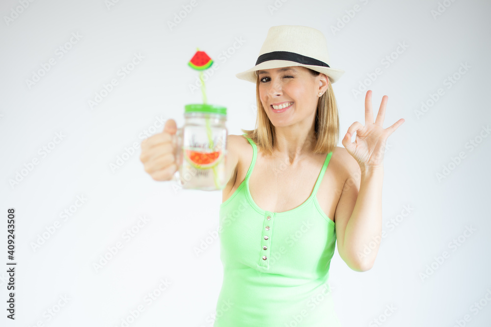 Happy young woman holding cold drink showing okay sign with fingers isolated over white background Happy young woman holding cold drink showing okay sign with fingers isolated over white background