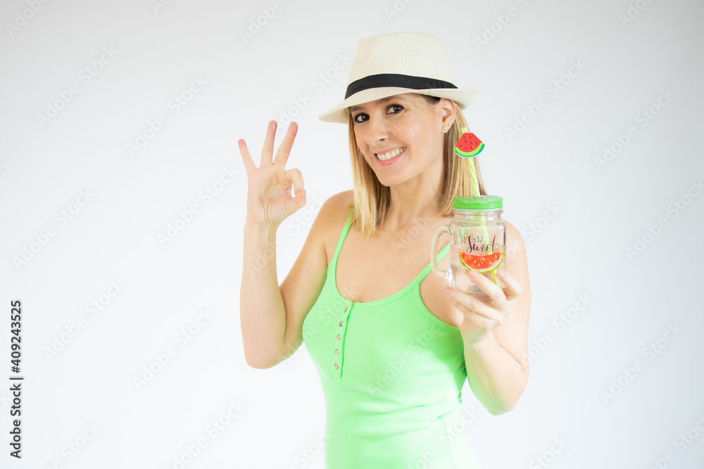 Happy young woman holding cold drink showing okay sign with fingers isolated over white background Happy young woman holding cold drink showing okay sign with fingers isolated over white background