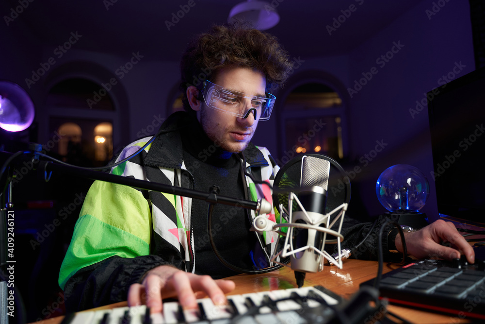 Young composer making a music with modern musical equipment a Midi keyboard  a Drum pad and a Microphone in dark room. Stock Photo | Adobe Stock