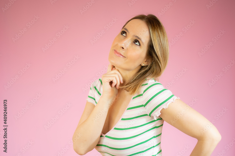 Happy young woman in striped t-shirt thinking over pink background. Happy young woman in striped t-shirt thinking over pink background.