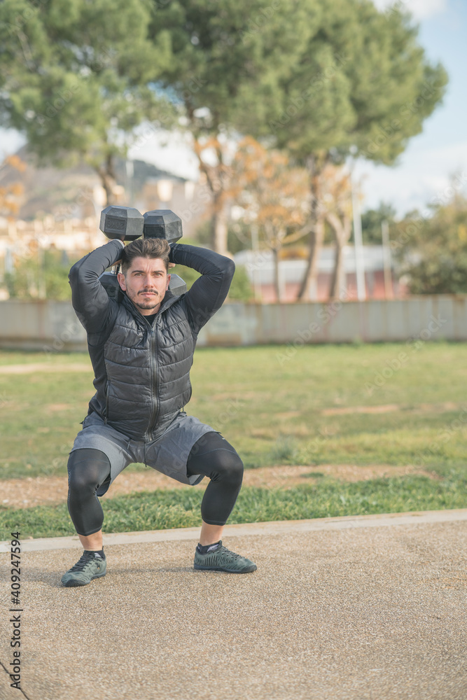 athletic man doing squat and back exercise and cross training with dumbbells