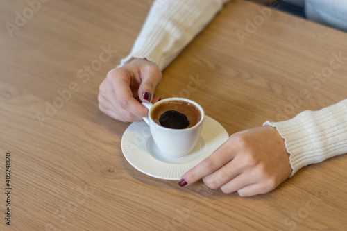 The woman on the wooden table holding Turkish coffee with your hands