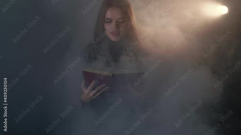 Young attractive caucasian woman holds a book and reads it, and then gets up from the sofa continuing to read on the go, passing through the smoke Young attractive caucasian woman holds a book and reads it, and then gets up from the sofa continuing to read on the go, passing through the smoke