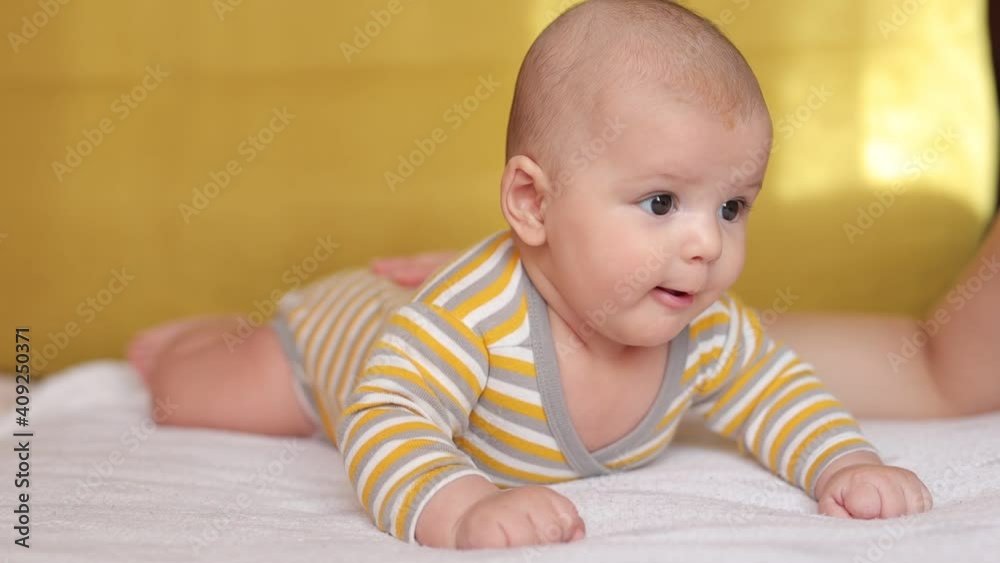 Adorable newborn baby in bodysuit in sunny bedroom. Family morning at home. Smiling child looking at camera. Illuminating and Ultimate gray color of the year 2021. Adorable newborn baby in bodysuit in sunny bedroom. Family morning at home. Smiling child looking at camera. Illuminating and Ultimate gray color of the year 2021.