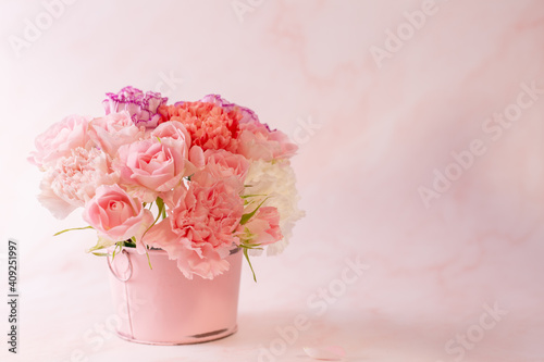 Mather's day concept. Colorful carnation and pink rose in a pink bucket