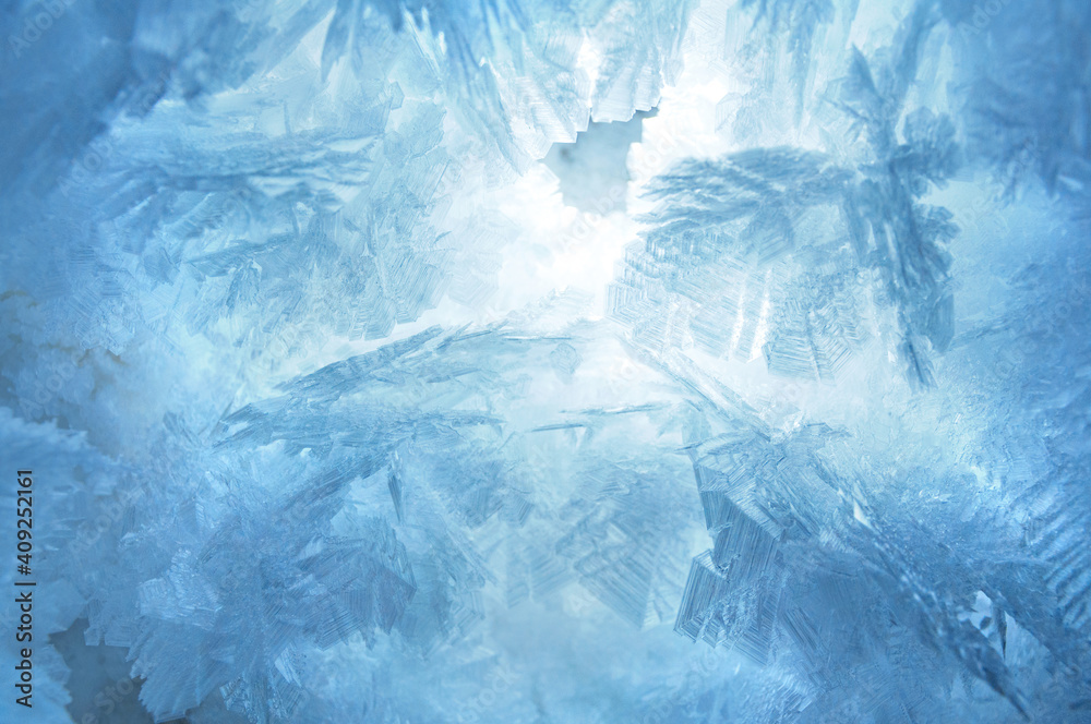 Fototapeta premium Abstract blue frozen pattern texture, frosted snowflakes close up background on the winter window 