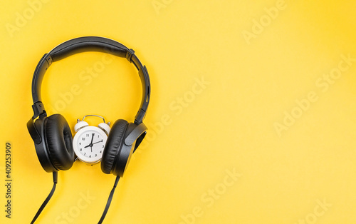 time to listen to music alarm clock and headphones on a yellow background