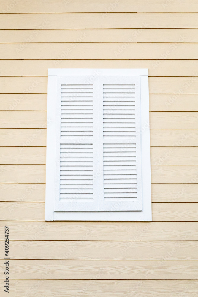 White Louvered Window Shutter on a Cream Wooden Building
