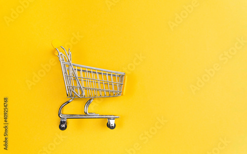 mini shopping cart on yellow background top view. Shopping concept. space for copying text