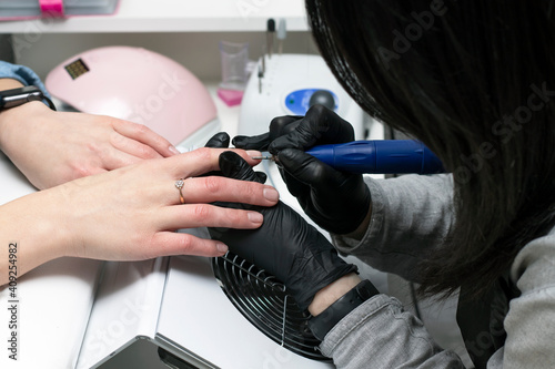 The master uses an electric clipper to remove nail polish during a manicure. Hardware manicure. Body care concept