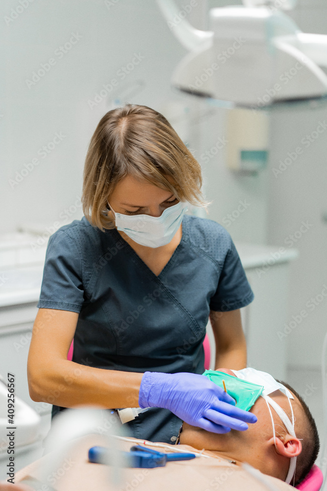 dentistry under general anesthesia. Dentist treats a patient with rubber dam Stock Photo Adobe