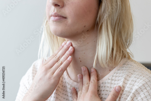 a young woman feels her thyroid gland photo