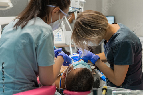 dentistry under general anesthesia. The dentist treats the patient under general anesthesia. dentist and assistant in the process. photo