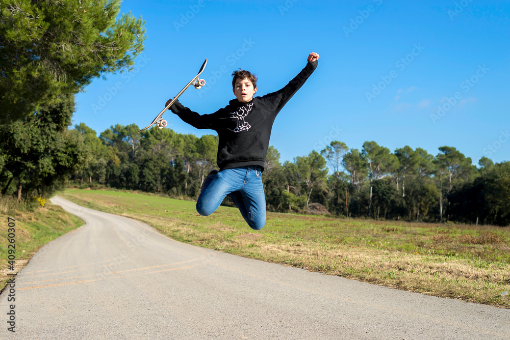 Action shot of a young skater teen male jumping high on a hill road Action shot of a young skater teen male jumping high on a hill road