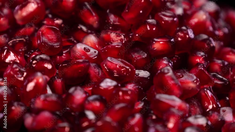Heap of pomegranate grains close up. Red seeds of grenade rotating, macro view.