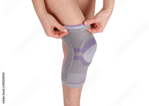 Fototapeta Naklejka Na Ścianę i Meble -  Knee Support Brace on leg isolated on white background. Orthopedic Anatomic Orthosis. Braces for knee fixation, injuries and pain. Orthotics. Foot orthosis. Knee Joint Bandage Sleeve. Elastic Sports