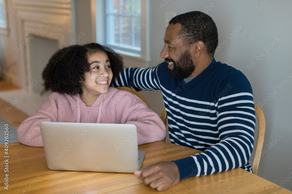An African-American father and tween daughter smile at each other An African-American father and tween daughter smile at each other