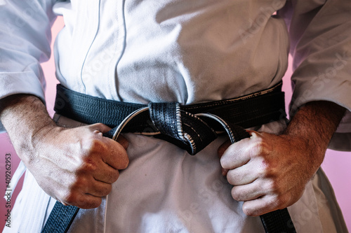 Unrecognizable karateka with black belt in firm position