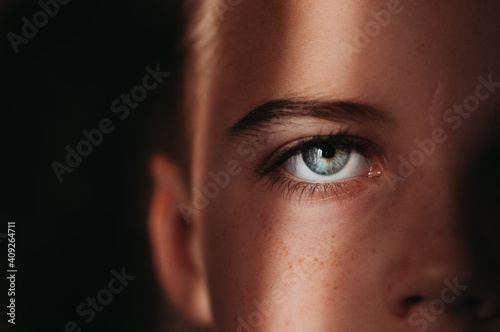 Close up of child's blue eye with black background in beam of light photo