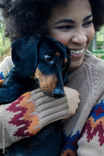 African American girl sitting and hugging her dog in the park in autumn photo