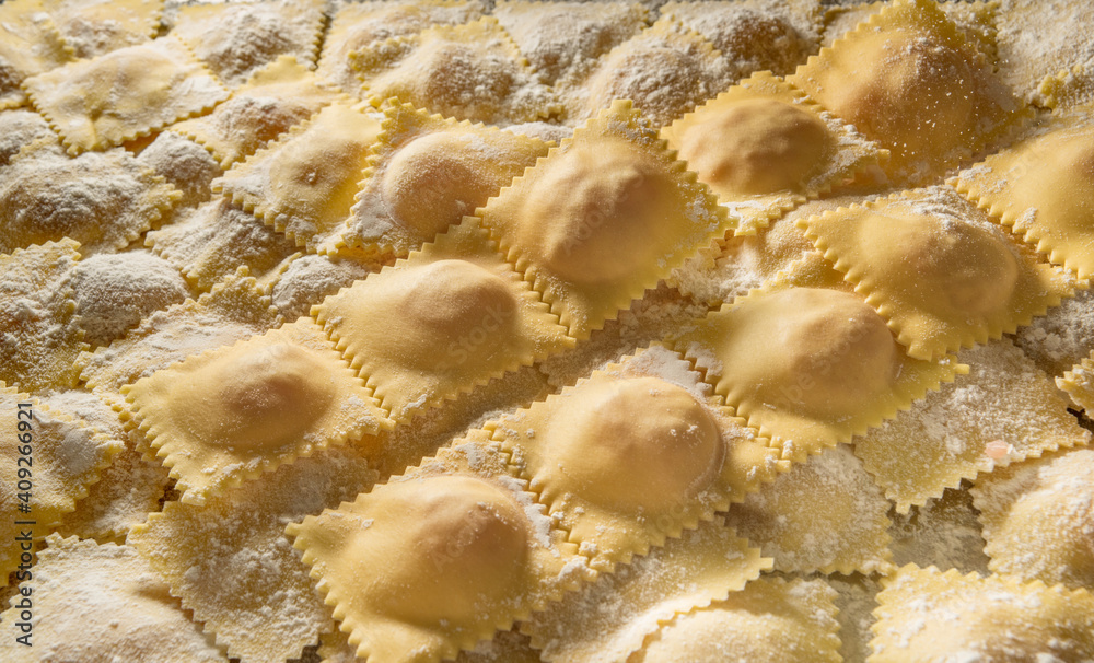 raw ravioli with flour, typical Italian stuffed egg pasta, close up, top view raw ravioli with flour, typical Italian stuffed egg pasta, close up, top view