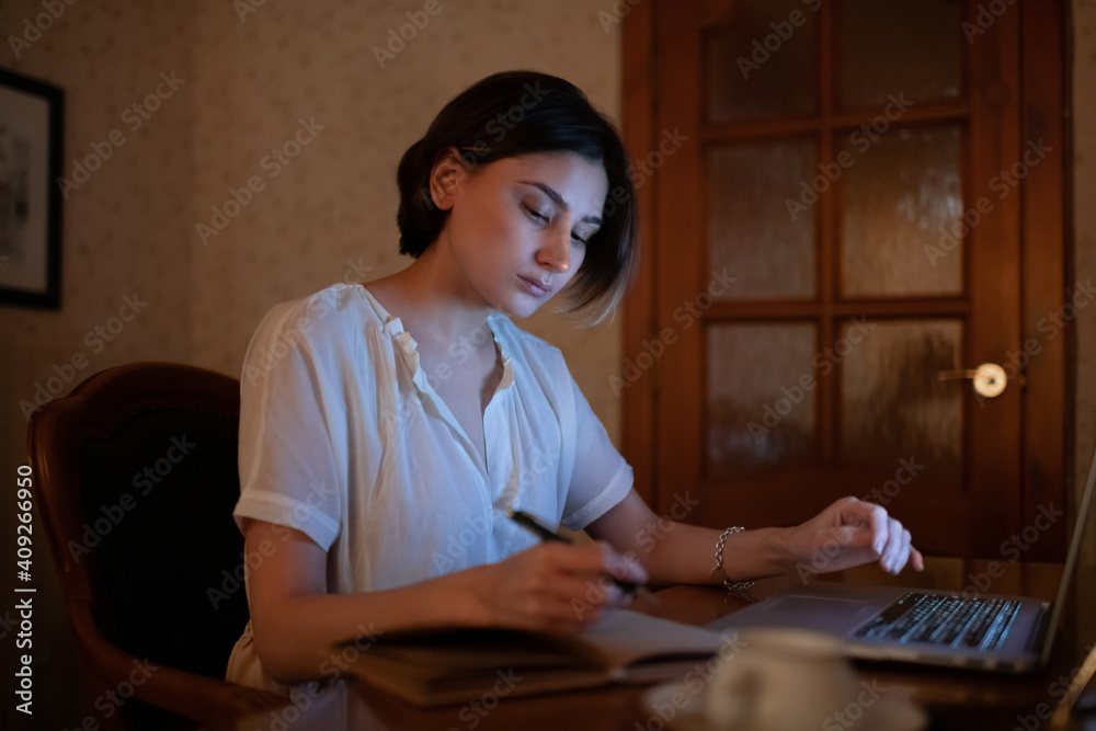 Young woman using laptop and writing Young woman using laptop and writing
