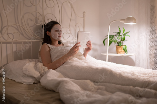 Woman with sheet mask watching film photo