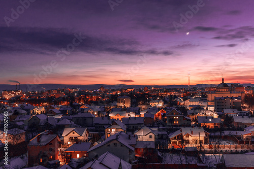 Evening sky over the winter city. Incredible color of the sky at sunset. The moon over the illuminated evening city