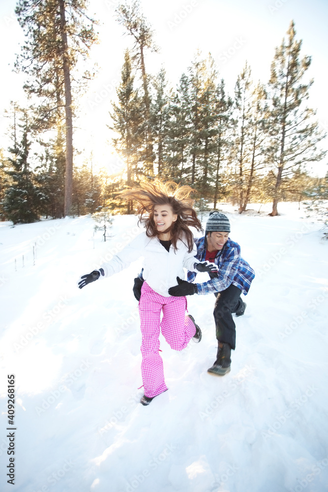 Man playfully chasing woman in snowy forest Man playfully chasing woman in snowy forest