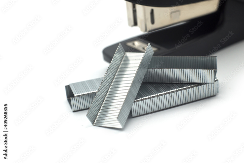 Closeup of staples pile and black slaper on white background Closeup of staples pile and black slaper on white background