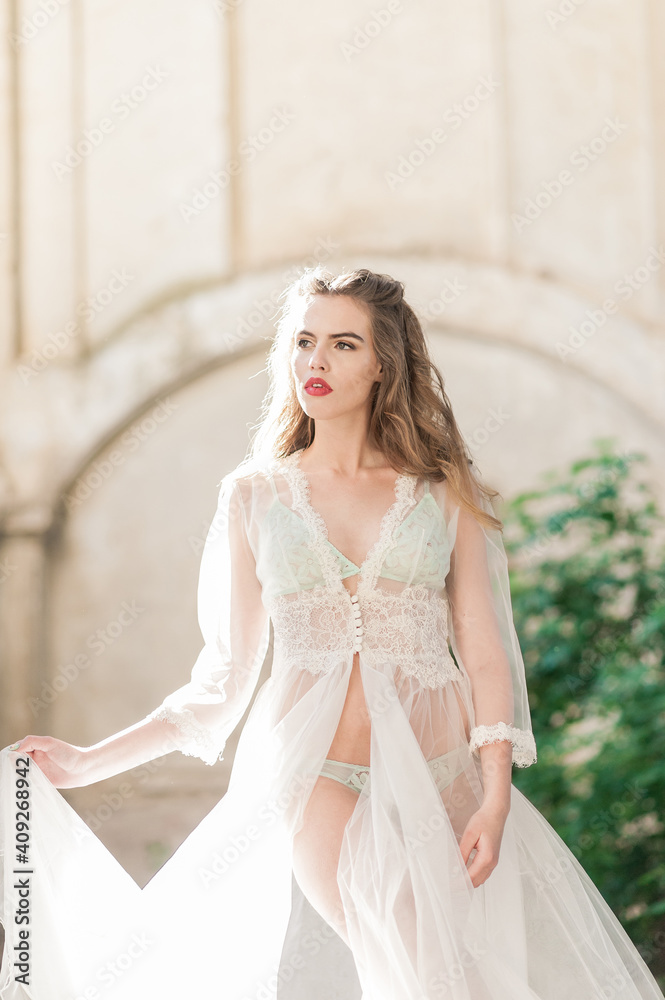 Fashion Portrait of sexy blonde woman in boudoir lace dress with jewelry. Bride's morning. Fine art wedding. Beautiful lady with wedding hairstyle long curly hair and bridal makeup.