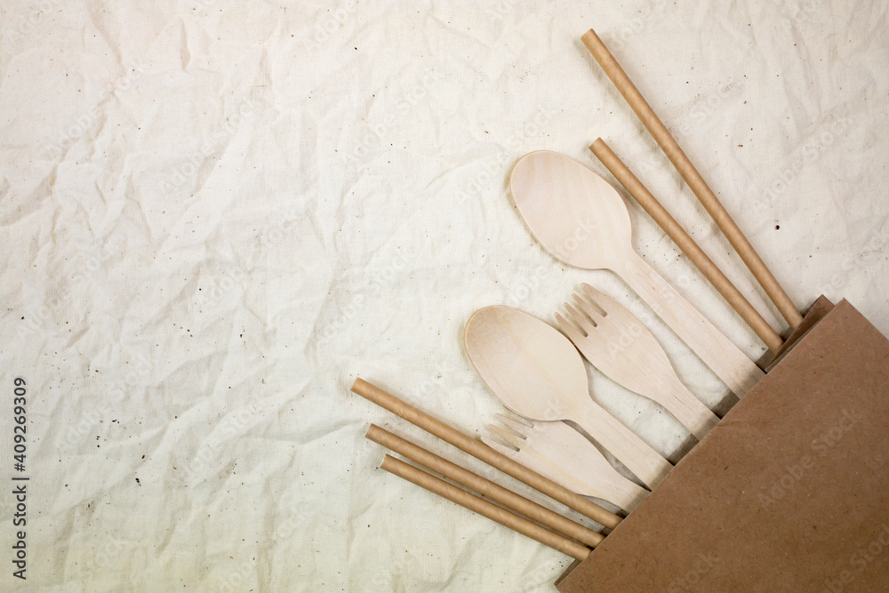 Disposable bamboo cutlery in a kraft bag on a canvas background. Plastic free concept. Flat lay. Disposable bamboo cutlery in a kraft bag on a canvas background. Plastic free concept. Flat lay.