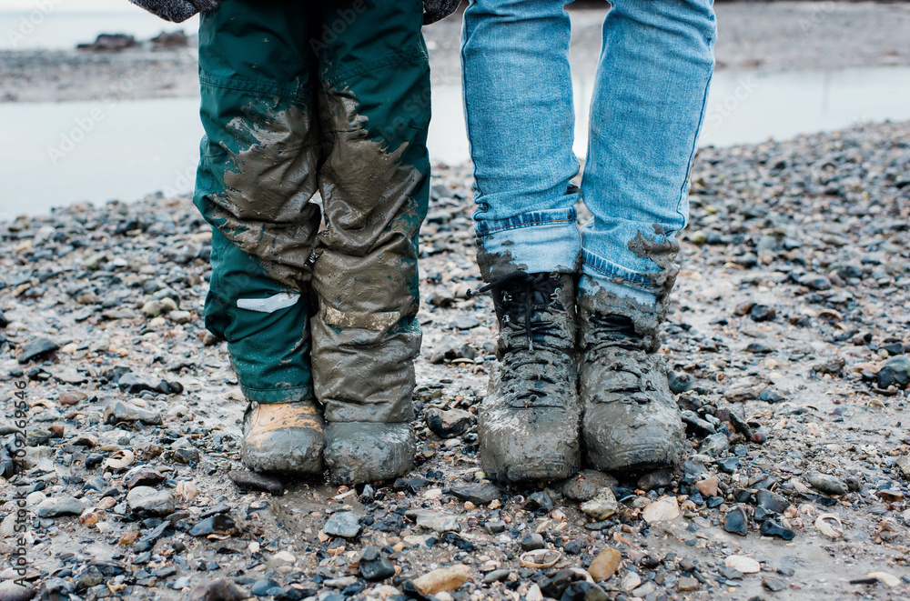 father and sons legs covered in mud after a walk by the sea together father and sons legs covered in mud after a walk by the sea together