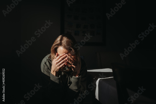 Woman with head in hands with dark background